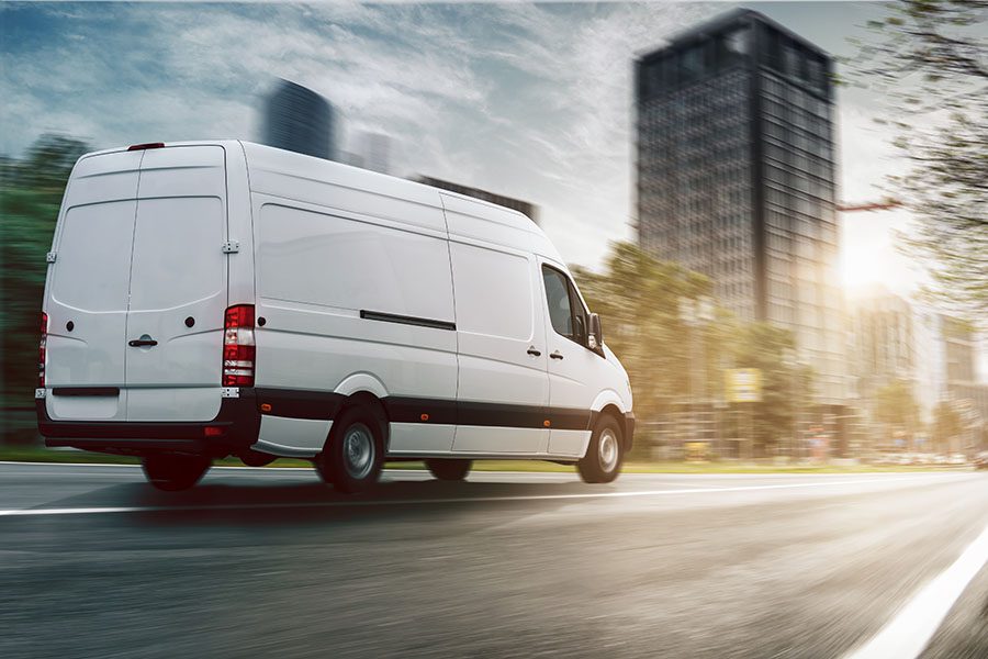 Business Insurance - White Commercial Van Driving Through Business District in a City